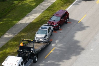 Tow truck loading crashed car on accident site. Emergency services personnel and vehicles responding to vehicle crash on American street. First responders helping on road in the USA.