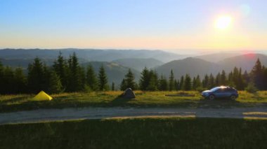 Güneşli bir akşamda kamp çadırları ve SUV arabaları dağ kampında. Etkin turizm ve off-road konsepti.
