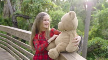 Çocuk kız, oyuncak ayısı arkadaşıyla birlikte tropikal yağmur ormanları yürüyüş parkuruna tutkuyla götürüyor. Arkadaşlık değerleri kavramı.