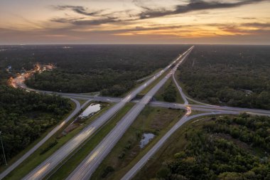 Gün batımında hızlı giden arabalarla Florida, ABD 'de geniş çoklu yol kavşağı. Amerikan ulaşım altyapısının üstü..