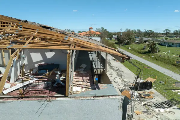 stock image Wind destroyed house roof and walls with missing asphalt shingles after hurricane Ian in Florida. Demolition of building after natural disaster.