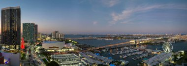 Aerial view of Skyviews Miami Observation Wheel at Bayside Marketplace with reflections in Biscayne Bay water and high illuminated skyscrapers of Brickell, citys financial center at night.