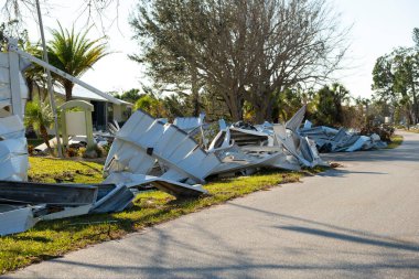 Kasırganın yol kenarındaki metal çöpler Florida yerleşim bölgesindeki evlere ağır hasar vermiş. Doğal afetten sonra.