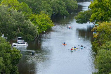 Hurricane Debby victims kayaking on flooded street in Sarasota, Florida. Rainfall flood waters between rural homes in residential area. clipart