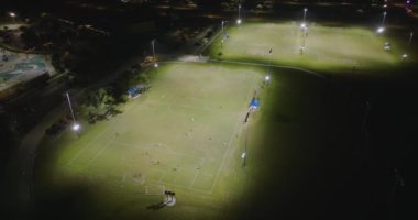 Geceleri çimen stadyumunda futbol maçına katılan insanların olduğu parkın havadan görüntüsü. Aktif yaşam konsepti.