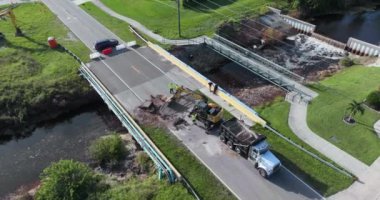 Yol yapımı. Kazıcı, Florida 'daki asfaltı sel baskınından sonra yıkılan köprüyü onardı. Yol çalışması alanında inşaat işçileri.