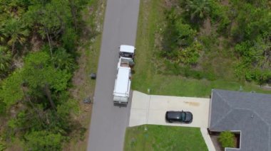 Çöp kamyonu banliyödeki çöp kutularını topluyor.