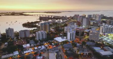Gün batımında şehir merkezinde Sarasota şehrinde yüksek binalar ve ufukta Ringling Köprüsü var. Florida 'da gayrimenkul geliştirme. ABD seyahat hedefi.
