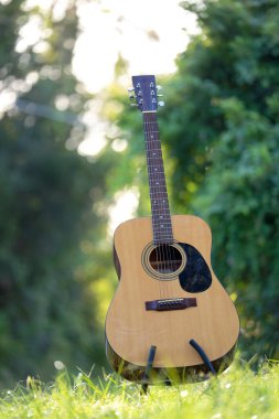 Acoustic guitar outdoors on greenery background. Concept of calm music.