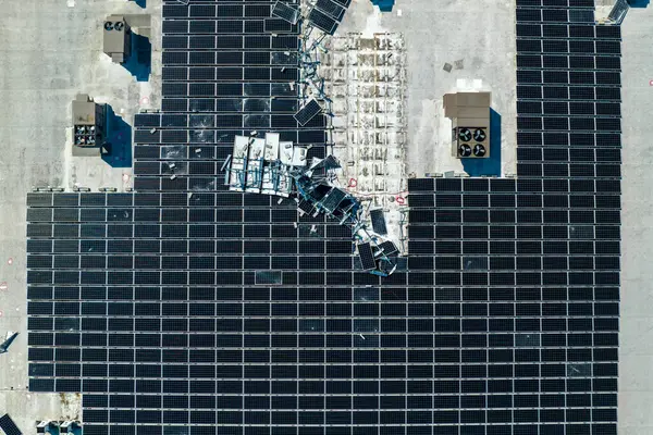 stock image Aerial view of damaged by hurricane wind photovoltaic solar panels mounted on industrial building roof for producing green ecological electricity. Consequences of natural disaster.