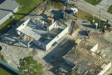 Florida 'nın banliyö bölgesinde ahşap iskeleti olan bitmemiş bir konutun çatı inşaatında çalışan inşaatçılar. Konut geliştirme kavramı.