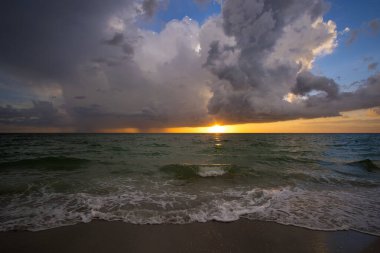 Gün batımında karanlık okyanusa sağanak yağmur yağıyor. Kasırga mevsiminde aşırı Florida havası.