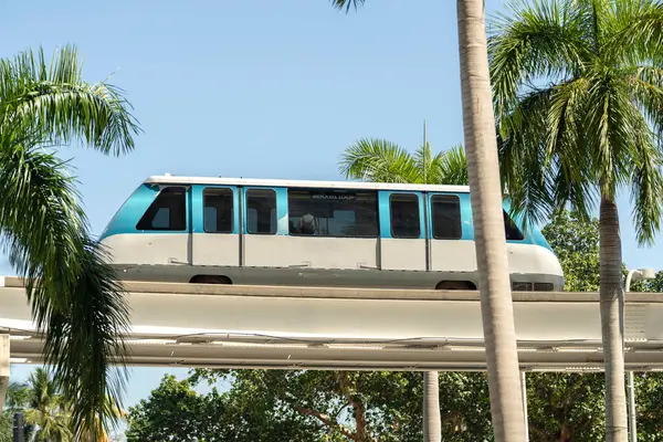 stock image Elevated train for public transportation in Miami city downtown in Florida USA. Metrorail train car on high railroad over street traffic between skyscraper buildings in modern American urban area.