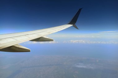 Gökyüzünde yüksekten uçan ticari jet kanadının uçak penceresinden bakın. Hava yolculuğu konsepti.