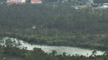 Florida orman ormanlarında yangın söndürmek için havadan su dolduran itfaiye helikopterinin görüntüsü. Acil servis helikopteri ormanda yangın çıkarmaya çalışıyor..