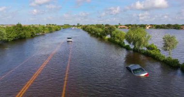 Kasırga yağmuru yolu sular altında bıraktı. Florida yerleşim bölgesinde, şehir caddesinde boğulan arabalar. Kasırga doğal felaketinin sonuçları.