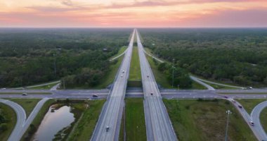 ABD karayolu taşımacılık altyapısı. Florida 'da otoyol kavşağında gün batımında hızlı giden arabalar var..