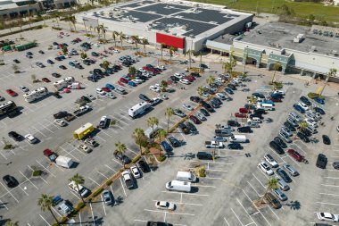 Bir marketin önündeki otoparkta park edilmiş birçok arabanın hava görüntüsü..