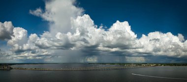 Heavy thunderstorm approaching traffic bridge connecting Punta Gorda and Port Charlotte over Peace River. Bad weather conditions for driving during rainy season in Florida. clipart