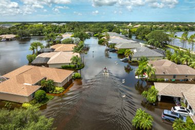 Debby Kasırgası kurbanları Sarasota, Florida 'da sel basmış bir sokakta teknede yüzüyorlar. Yerleşim alanındaki kırsal evler arasında sağanak yağmur suları.