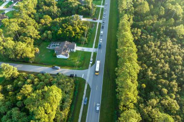 Standart Amerikan okul otobüslerinin en üst görüntüsü sabah erken saatlerde kasaba merkezindeki sokak durağından çocukları alıyor. ABD 'de toplu taşıma.