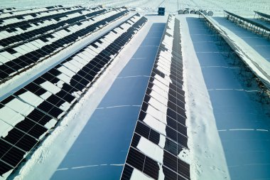 Aerial view of electrical power plant with solar panels covered with snow melting down in winter end for producing clean energy. Concept of low effectivity of renewable electricity in northern region.