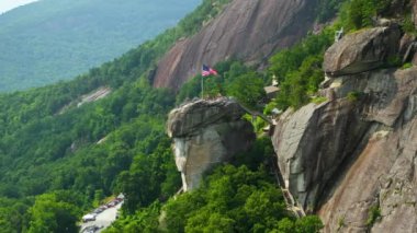 Chimney Rock 'ın hava görüntüsü, Amerikan ulusal bayrağı ve birçok turist Kuzey Carolina' daki Chimney Rock State Park 'ta. Appalachian dağlarında gidilecek yer