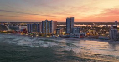 Günbatımında Daytona Plajı şehri. Parlak lüks oteller ve apartmanlar. Florida 'daki kıyı mimarisinin havadan görünüşü. Güney Amerika 'da turizm altyapısı