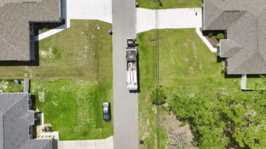 Çöp kamyonu Amerikan mahallesinin kaldırımından çöp kutusu yüklüyor.