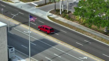 Amerikan bayrağı geniş çoklu şeritli yolda sürüş arabalarıyla dalgalanıyor. ABD 'de şehir ulaşımı. Amerikan şehir trafiği.