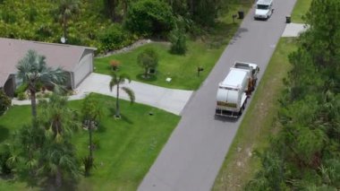 Çöp kamyonu Amerikan mahallesinin kaldırımından çöp kutusu yüklüyor.