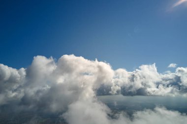 Dünya 'nın yüksek irtifasında, yağmur fırtınasından önce oluşan kabarık kümülüs bulutlarıyla kaplı uçak penceresinden hava görüntüsü.