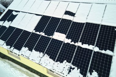 Aerial view of snow melting from covered solar photovoltaic panels installed on house rooftop for producing clean electrical energy. Low effectivity of renewable electricity in nothern region winter.