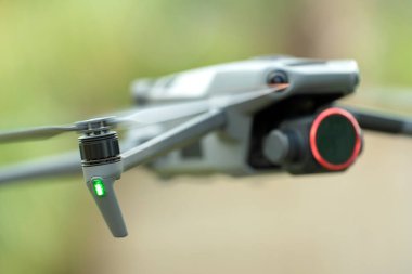 Drone quadcopter with digital camera and fast rotating propellers flying taking video and pictures.