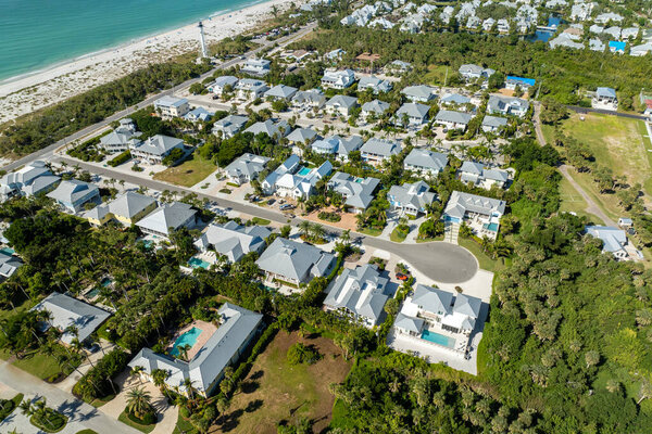 Вид с воздуха на богатый прибрежный район. Дорогие особняки между зелеными пальмами на берегу Мексиканского залива в островном городке Бока-Гранде на острове Гаспарилла на юго-западе Флориды, США.