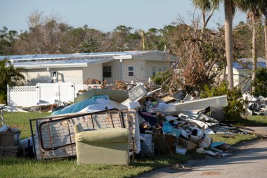 Kasırganın yol kenarındaki metal çöpler Florida yerleşim bölgesindeki evlere ağır hasar vermiş. Doğal afetten sonra.