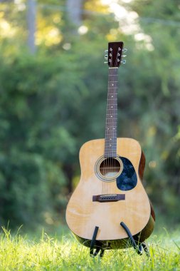 Acoustic guitar outdoors on greenery background. Concept of calm music.