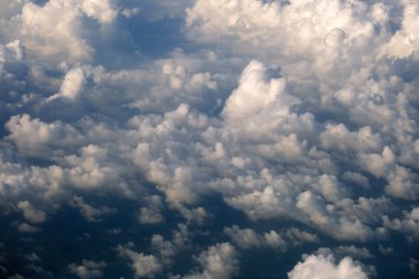 Yüksek irtifada, yoğun kümülüs bulutlarının uçtuğu uçak penceresinden hava görüntüsü.