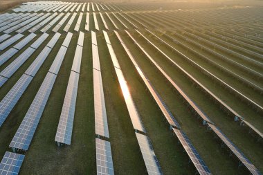 Akşamları temiz elektrik enerjisi üretmek için sıra sıra güneş fotovoltaik panelleri olan sürdürülebilir büyük elektrik santralinin havadan görünüşü. Sıfır emisyonlu yenilenebilir elektrik kavramı.