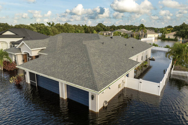 Flooding in Florida caused by tropical storm from hurricane rainfall. Suburb houses in residential community surrounded by flood waters. Aftermath of natural disaster.