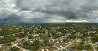Landscape of dark ominous clouds forming on stormy sky during heavy thunderstorm over rural town area.