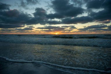 Yumuşak akşam deniz dalgalarının kumlu sahilde ezdiği okyanus batımı manzarası..