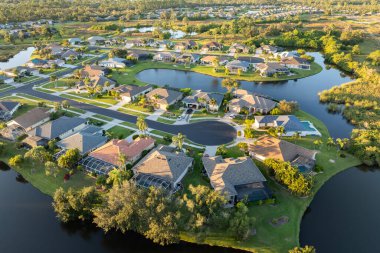 Gün batımında Florida yerleşim bölgesindeki özel evlerin hava görüntüsü. Amerikan banliyölerinde emlak gelişimine örnek olarak yeni aile evleri.