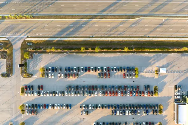 Geniş Amerikan otoyolunun yakınında satılık bir sürü yeni arabasıyla bayilik otoparkının havadan görüntüsü. ABD otomotiv sanayii kavramının geliştirilmesi.