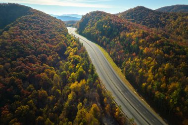 Empty free of vehicles I-40 freeway road leading to Asheville in North Carolina thru Appalachian mountains with yellow fall forest. High gas prices and energy crisis concept.