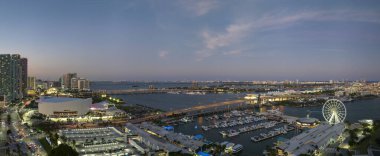 High illuminated skyscrapers of Brickell, citys financial center. Skyviews Miami Observation Wheel at Bayside Marketplace with reflections in Biscayne Bay water and US urban landscape at night. clipart