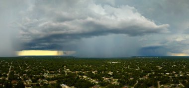 Landscape of dark ominous clouds forming on stormy sky during heavy thunderstorm over rural town area.