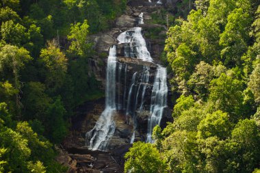 Nantahala Ulusal Ormanı 'ndaki kayalık kayaların arasına temiz su dökülen büyük şelaledeki orman sularıyla muhteşem bir yaz manzarası. Whitewater Şelalesi, Kuzey Carolina, ABD.