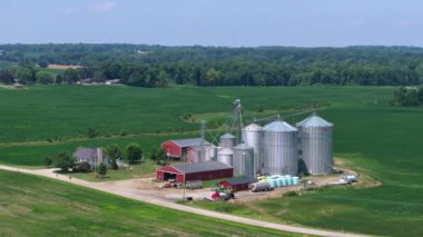 ABD 'nin orta batısındaki yeşil tarım arazileri arasında kırsal tarım çiftliği ve tahıl ambarları. Amerikan tarım arazisi.