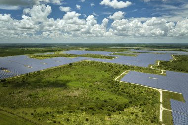 Aerial view of sustainable electric power plant between agricultural farm fields with solar photovoltaic panels for producing clean electrical energy. Renewable electricity with zero emission concept.